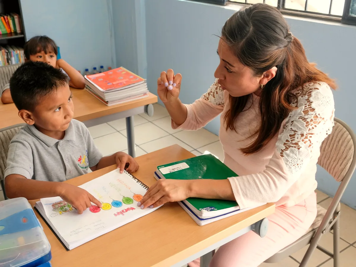 Profesora repasando un cuaderno de ejercicios con un alumno