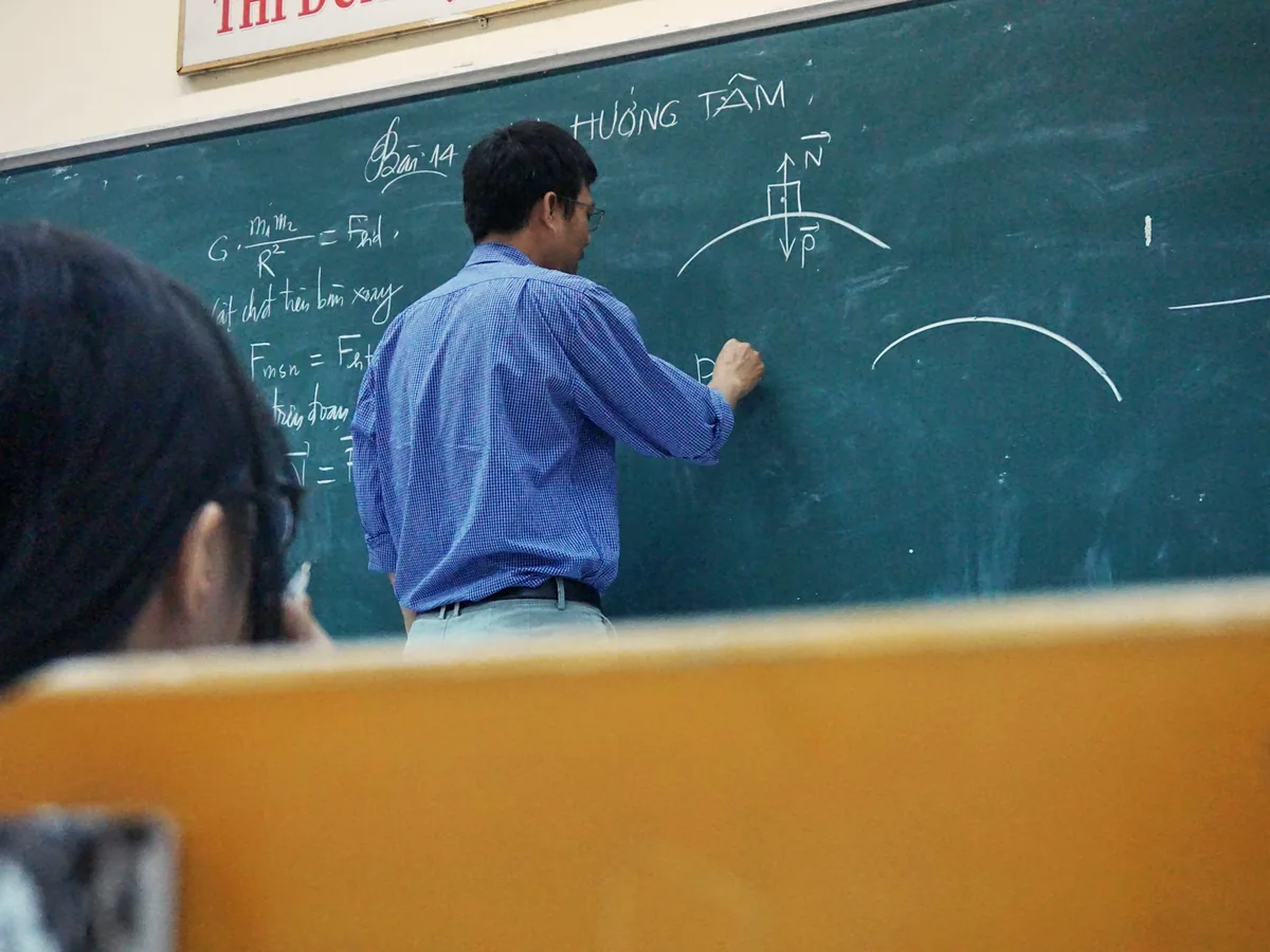 Profesor desarrollando ecuaciones de física en la pizarra