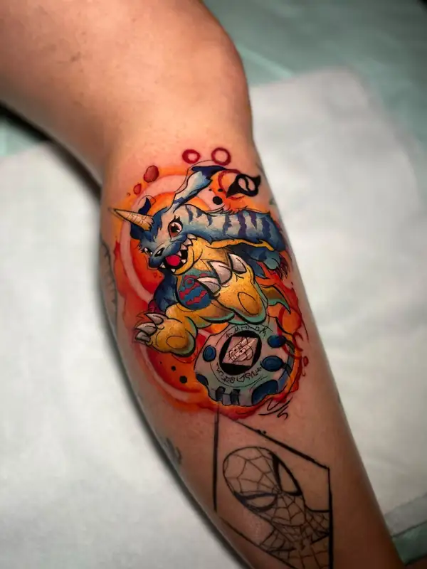 Gabumon, de Digimon, y su digivice, a color sobre una mancha roja y naranja, en la pierna.