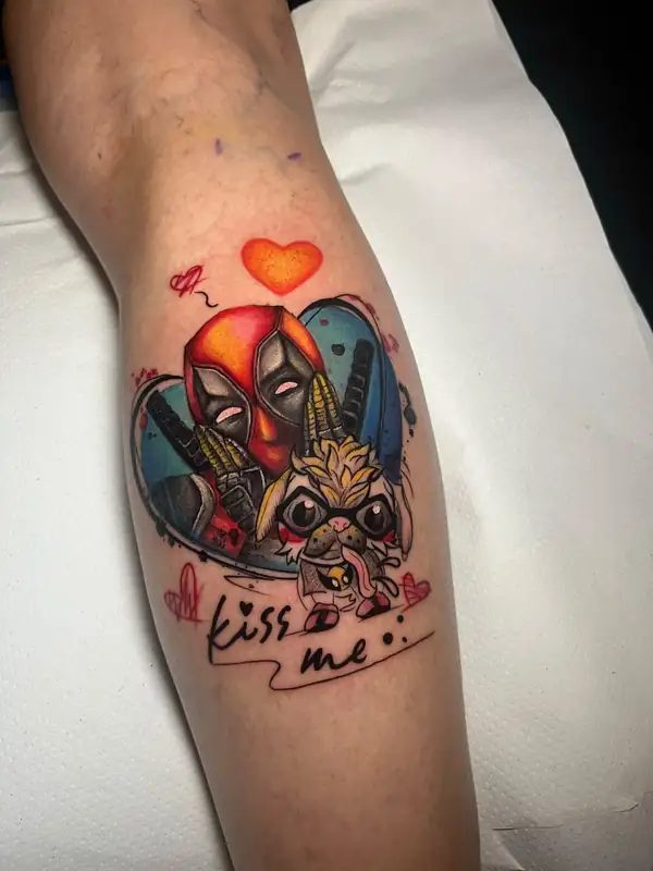 Deadpool en pequeño junto a otro personaje, dentro de un corazón y con las palabras «kiss me», a color en la pierna.