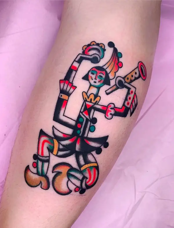 Figura con máscara, tocado de plumas y traje de colores que toca un cuerno, en tradicional a color en la pierna.