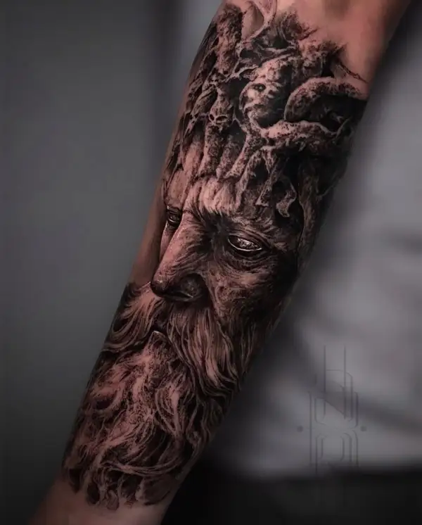Rostro de anciano que sale de un árbol, en negro y grises en el antebrazo.