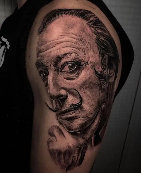 Retrato de Salvador Dalí con su bigote, en negro y grises en el hombro.