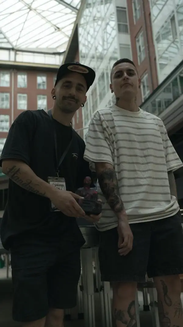 Haroz y su cliente en una convención de tatuaje, con el trofeo del primer premio.