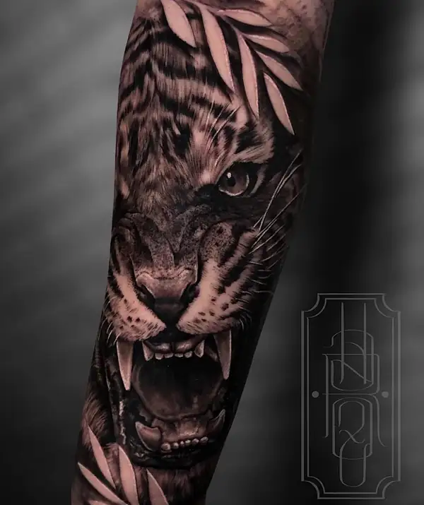 Tigre rugiendo entre hojas, en realismo en negro y grises en el antebrazo.