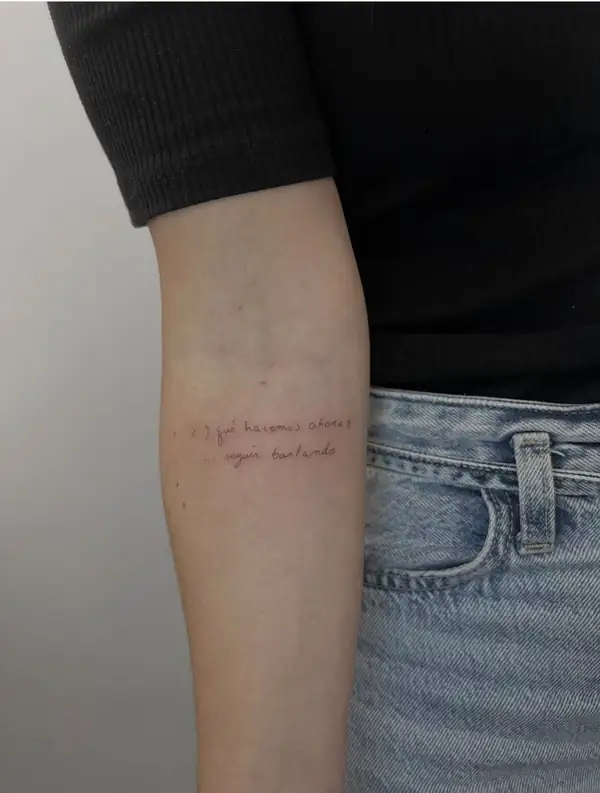 Una frase en dos líneas, en letra fina, en el antebrazo.