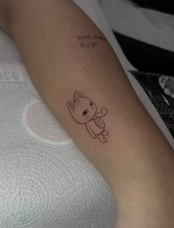Un gato de dibujos saludando, en línea fina, con una frase encima, en el brazo.