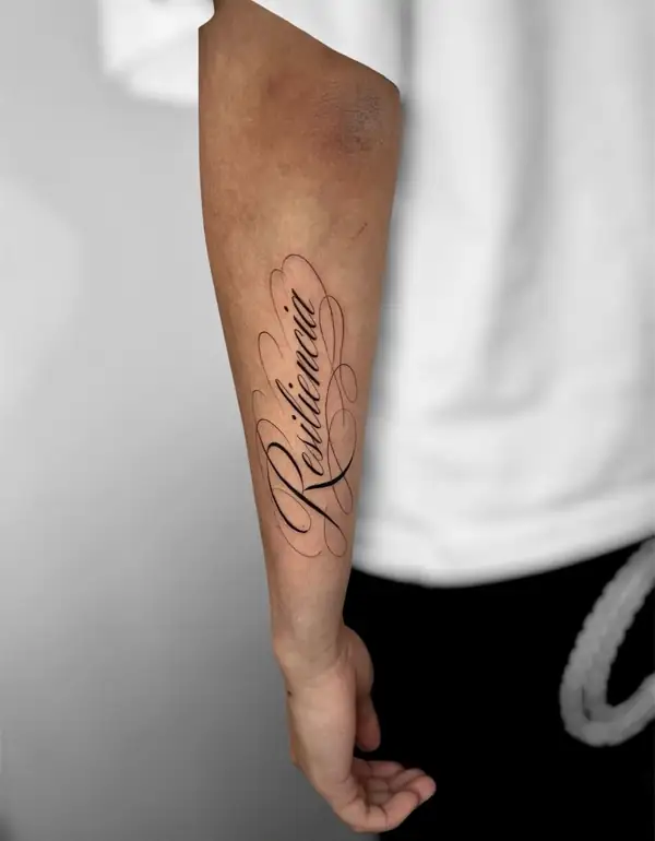 La palabra «Resiliencia» en letra caligráfica a lo largo del antebrazo.
