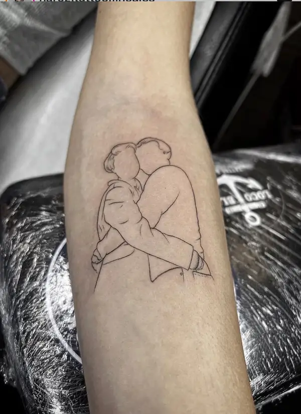 Una pareja abrazada dibujada solo con línea fina, en el antebrazo.