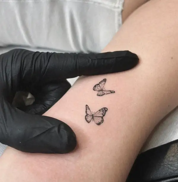 Dos mariposas pequeñas en línea fina y sombra, en el antebrazo.