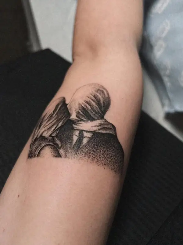 «Los amantes» de Magritte, dos figuras besándose con la cabeza tapada, en puntillismo en el antebrazo.