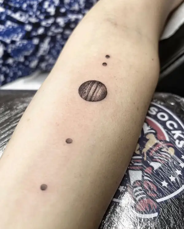 Planetas en fila, de mayor a menor, hechos a puntos en el antebrazo.