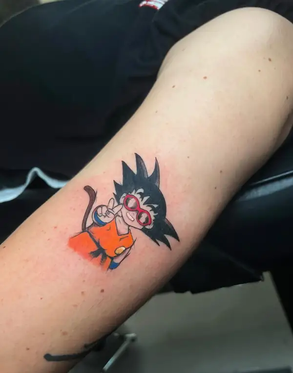 Goku de niño con gafas rojas, pequeño y a color, en el brazo.