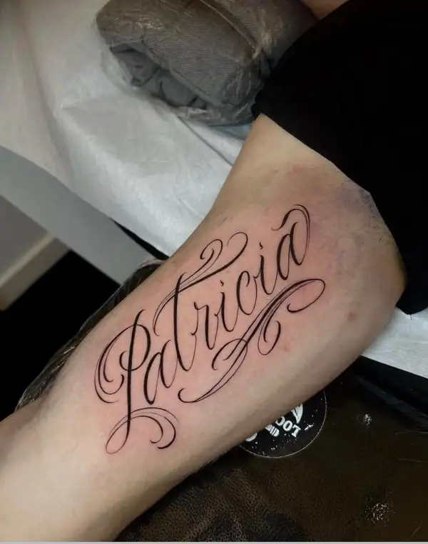 Un nombre en letra caligráfica grande en el brazo.