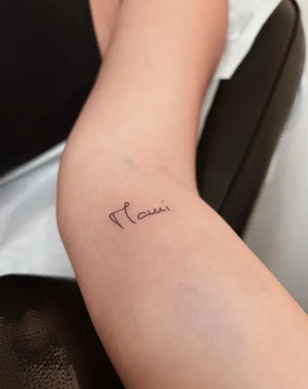 Una palabra escrita a mano, pequeña, en el brazo.