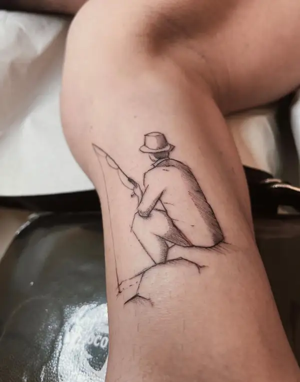 Un hombre con sombrero sentado en una roca, pescando, en línea fina en el brazo.