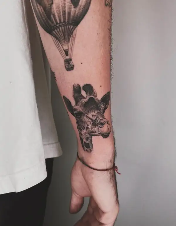 Una jirafa en puntillismo y, encima, un globo aerostático, en el antebrazo.