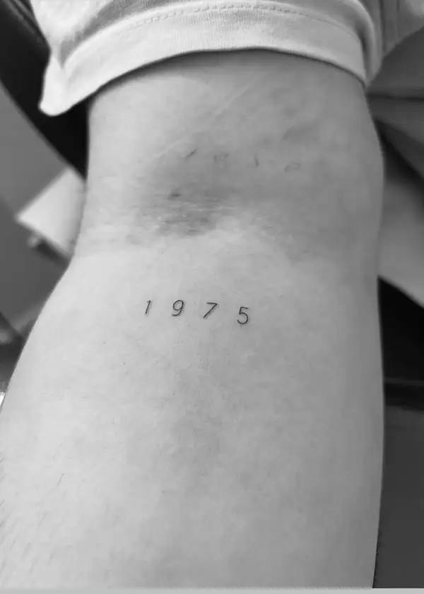 El año «1975» en números finos en el antebrazo.