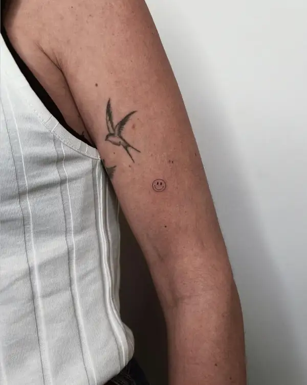 Una golondrina pequeña y una cara sonriente en el brazo.