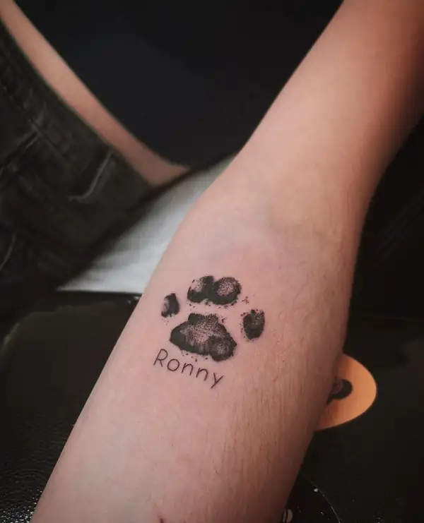 La huella de una pata con el nombre de la mascota debajo, en el antebrazo.