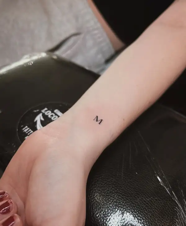 Una letra «M» pequeña en la muñeca.