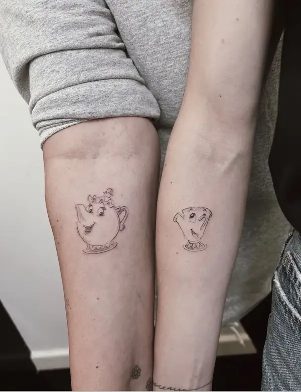 La señora Potts y Chip, de La bella y la bestia, uno en cada antebrazo de dos personas, en línea fina.