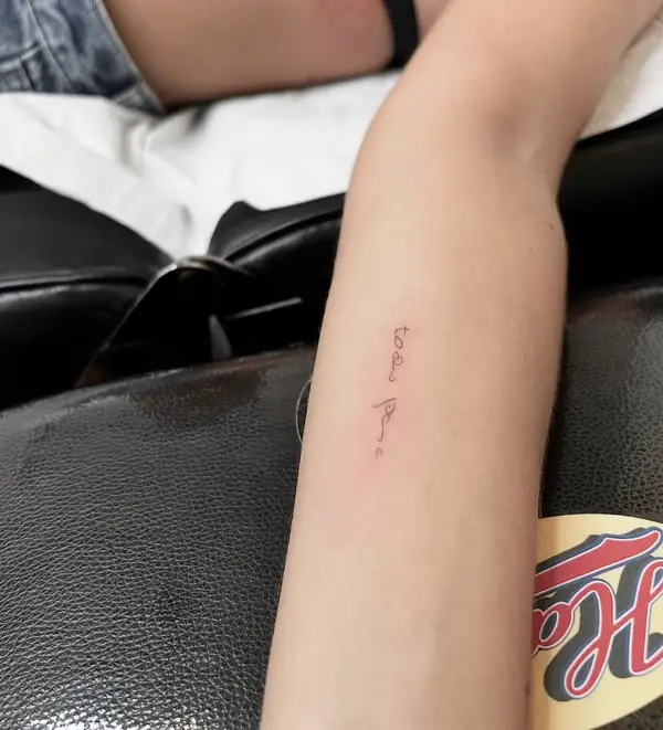 Una frase corta en letra fina a lo largo del antebrazo.
