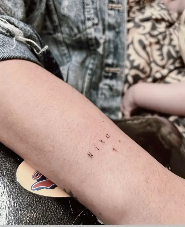 Un nombre en letras pequeñas en el antebrazo.