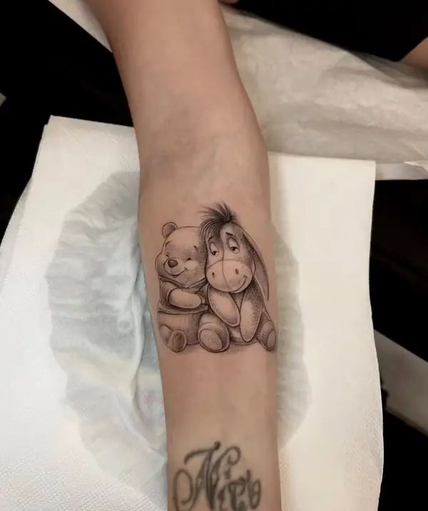 Winnie the Pooh e Ígor abrazados, en puntillismo en el antebrazo.