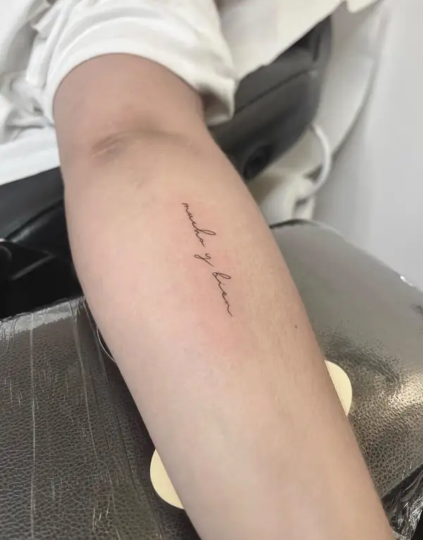 Una frase en letra cursiva fina a lo largo del antebrazo.