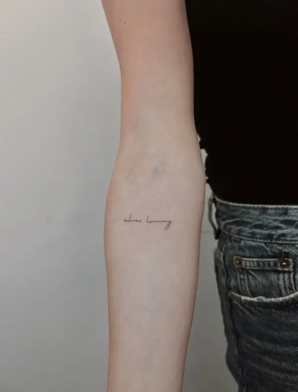 Una palabra en letra fina en el antebrazo.