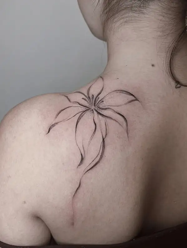 Una flor de pétalos largos en línea fina que baja del hombro por la espalda.