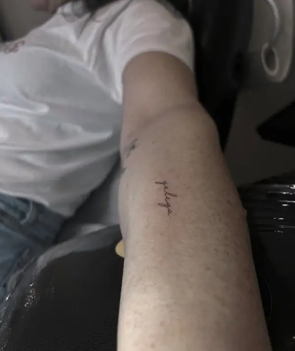 Una palabra en letra fina en el brazo.