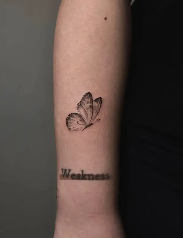 Una mariposa en línea fina y la palabra «Weakness» en la muñeca.