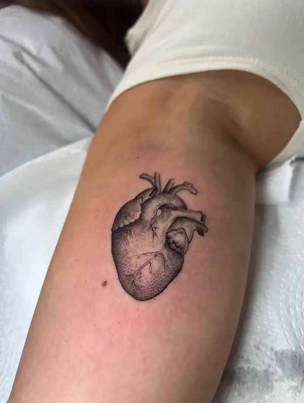 Un corazón anatómico pequeño, en punteado, en el brazo.
