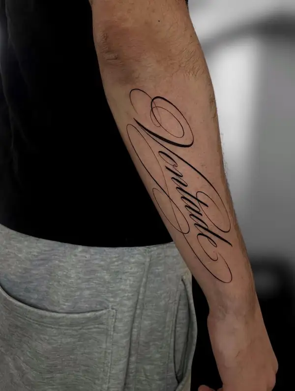 Una palabra en letra caligráfica grande a lo largo del antebrazo.