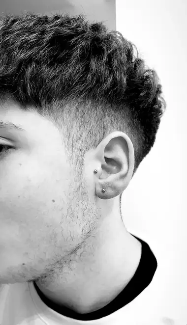 Dos bolitas en el lóbulo, una encima de otra, de perfil, en blanco y negro.